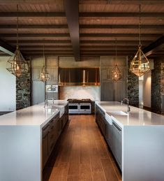 a large kitchen with an island counter top and two ovens in the center, surrounded by hanging lights