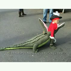 a little boy in a costume is playing with an alligator