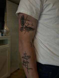 a man's arm with a cross and bird tattoo on the left side of his arm