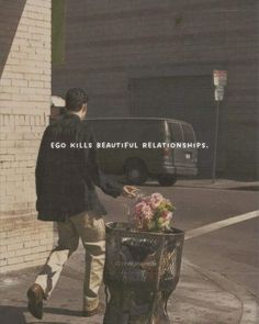 a man walking past a trash can with flowers in it