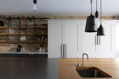 a kitchen with wooden counter tops and hanging lights over the sink, along with white cabinets