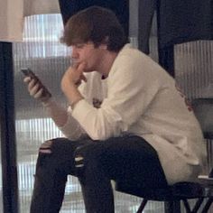 a man sitting in a chair looking at his cell phone