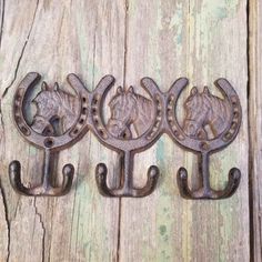 three metal horse head hooks on a wooden surface