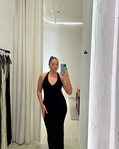 a woman in a black dress taking a selfie