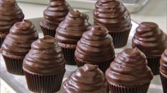 chocolate cupcakes with frosting sitting on a white plate next to each other