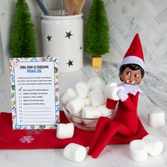 an elf is sitting next to marshmallows and a sign on the counter