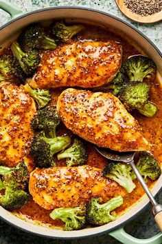 chicken and broccoli in a skillet with a wooden spoon on the side