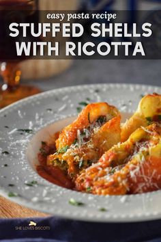 stuffed shells with ricotta on a white plate next to a glass of red wine