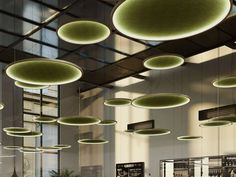 the ceiling is filled with hanging lights and round objects in green shades, as well as people sitting at tables