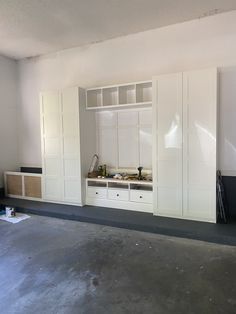 an empty room with white cabinets and drawers