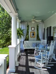 a porch with rocking chairs and curtains on it