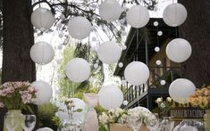 the table is set with white paper lanterns and floral centerpieces for an outdoor wedding reception