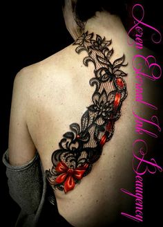 the back of a woman's shoulder with an intricate lace tattoo design on it