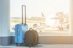 two pieces of luggage sitting in front of an airport window