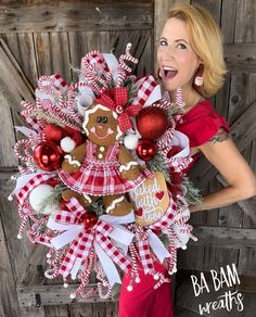 a woman is holding a christmas wreath with gingerbreads and ornaments on the front