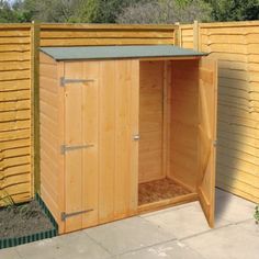 a large wooden shed sitting in the middle of a yard next to a fence and shrubbery