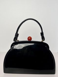 A vintage 1950's 1960's black patent leather handbag with an art Deco clasp in a cherry brown apple swirl Dey. Made by the brand AETN in the USA it features a beige lining and is in very good condition. Brown Apple, Cherry Brown, Patent Leather Handbags, Black Handbag, Black Patent Leather, Black Handbags, Clutch Handbag, Leather Handbag, Evening Bags