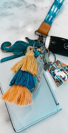 a keychain that has some tassels attached to it and is sitting on top of a card holder