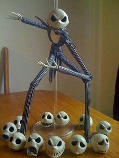 a skeleton figurine is posed on a table with seven small skulls around it