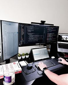 a person sitting at a desk with two monitors and a laptop on top of it