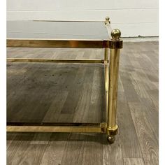 a glass and brass coffee table on wooden floor