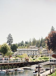 boats are docked in the water near a building and trees with people walking on it