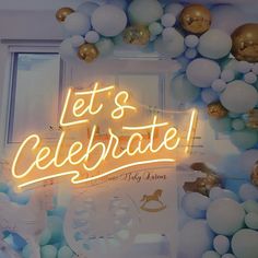 a neon sign that says let's celebrate surrounded by balloons