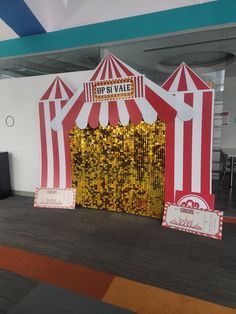 a large red and white striped circus tent with gold sequins on the floor