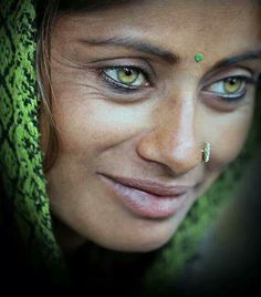 a woman with green eyes and piercings on her nose is smiling for the camera