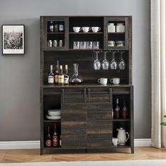 a wooden cabinet with wine glasses and liquor bottles on the top shelf, in front of a gray wall