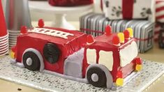 a cake shaped like a firetruck on a table with red and white plates