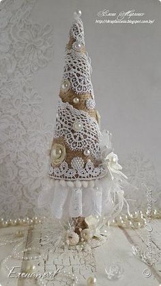 a white and gold christmas tree made out of doily on a lace tablecloth