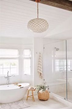 a white bath tub sitting next to a window in a bathroom under a light fixture