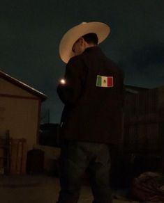 a man wearing a white cowboy hat standing in front of a building with his back turned to the camera