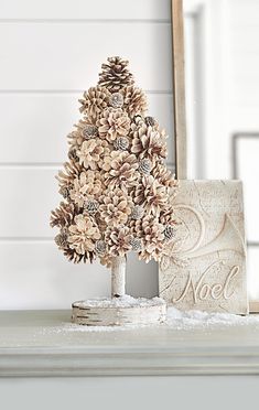 a small pine cone christmas tree sitting on top of a white mantle next to a mirror