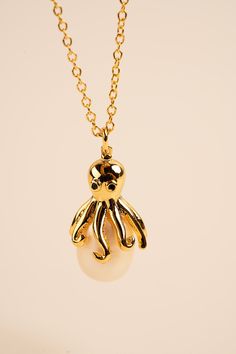 Our stunning Octopus Necklace features a beautifully crafted octopus pendant perched on top of a lustrous pearl. The intricate details of the octopus pendant capture the grace and beauty of these mysterious creatures, while the pearl adds a touch of elegance and sophistication. The pendant is suspended from a delicate chain, allowing it to rest perfectly on your neck. Crafted from high-quality materials, this necklace is both durable and comfortable to wear. It's perfect for any occasion, whether you're dressing up or keeping it casual. The Octopus Necklace with Pearl also makes a wonderful gift for anyone who loves sea creatures and ocean-inspired jewelry. It's a unique and thoughtful way to show someone you care. So why not add some nautical charm and elegance to your jewelry collection Sea Themed Jewelry, Single Pearl Necklace Gold, Mysterious Creatures, Octopus Jewelry, Pearl Necklace Gold, Octopus Necklace, Octopus Pendant, Weird Jewelry, Ocean Inspired Jewelry