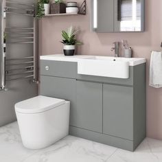 a white toilet sitting next to a bathroom sink under a mirror above a radiator