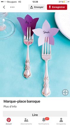 two forks with flowers on them sitting next to each other near plates and utensils