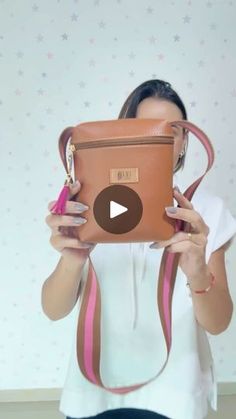 a woman holding up a brown purse in front of her face