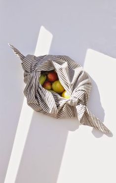 a striped bag with apples in it sitting on the floor next to a white wall