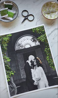 a couple standing next to each other in front of a table with scissors and plates