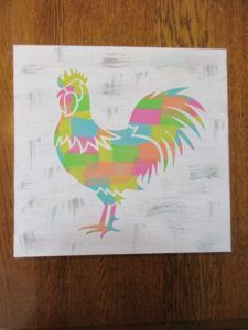 a chicken painted on a piece of white paper with multicolored squares in the shape of a rooster