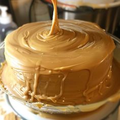 a chocolate cake is being drizzled with caramel icing on top