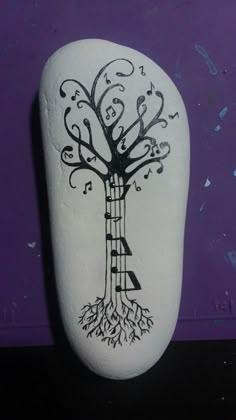 a rock with a tree painted on it and musical notes coming out of the top