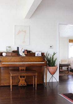 a living room with a grand piano in the corner and a potted plant next to it