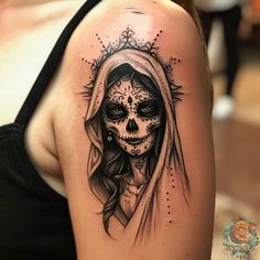 a woman's shoulder with a skull and veil tattoo on her left upper arm