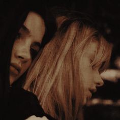 two women looking at each other with their faces close to one another in front of them