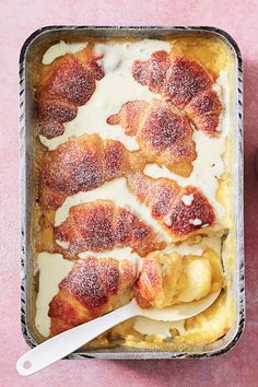 a pan filled with some kind of food on top of a pink countertop next to an apple