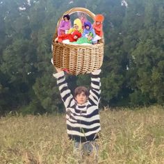 a young boy holding up a basket with toys in it