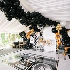 a party with black and white balloons, checkered table cloths and gold foil streamers